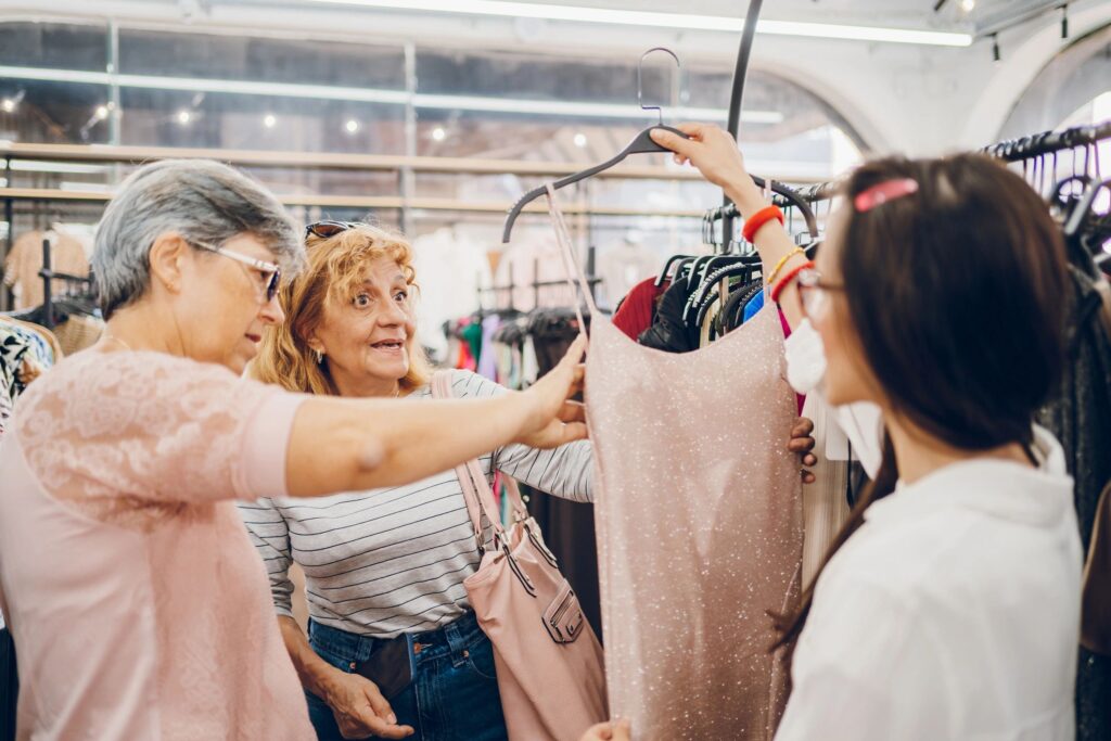 A saleswoman talking with two senior women in a clothing store.