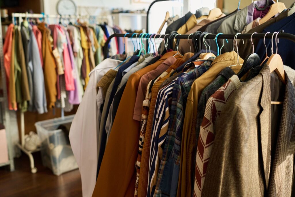 Assorted Vintage Clothing Hanging on Rack in Thrift Shop Interior Setting